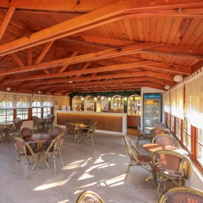 Un bar intérieur chaleureux avec une imposante charpente en bois et une ambiance feutrée.