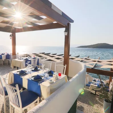 Des tables dressées sous une pergola en terrasse face au coucher du soleil.