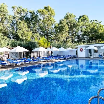 Un grand bassin entouré de nombreux transats et parasols blancs.