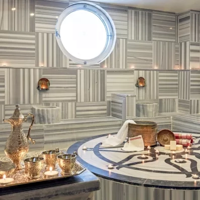 Un bain turc traditionnel aux parois de marbre, décoré de bougies et d'accessoires de soins.