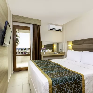 Une chambre avec un accès direct au balcon, une télévision murale et un bureau.