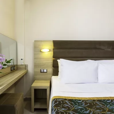 Zoom sur le coin nuit mettant en avant le chevet en bois clair du lit.