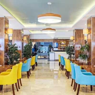 Un grand hall de réception, décoré de colonnes en bois et de plusieurs fauteuils.