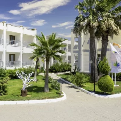 Un chemin à travers les jardins de l'hôtel, entre les palmiers et les bâtiments blancs des chambres.