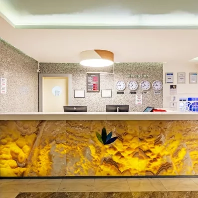 Un comptoir de réception élégant avec une façade en pierre et plusieurs horloges.