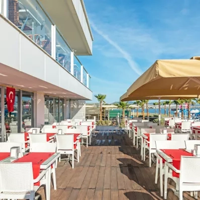 Une vaste terrasse ensoleillée avec des tables, située au pied d'un bâtiment moderne.