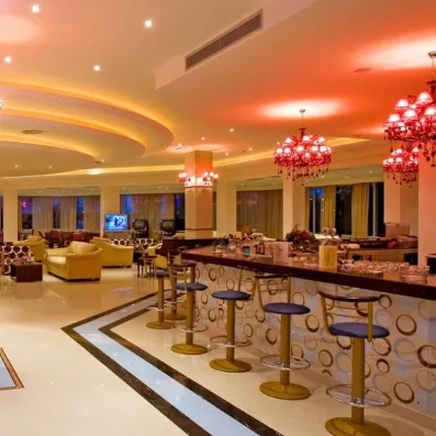 bar, lustres rouges, canapées jaunes et tables basses bois foncé rouge, grands tabourets de bar bleus