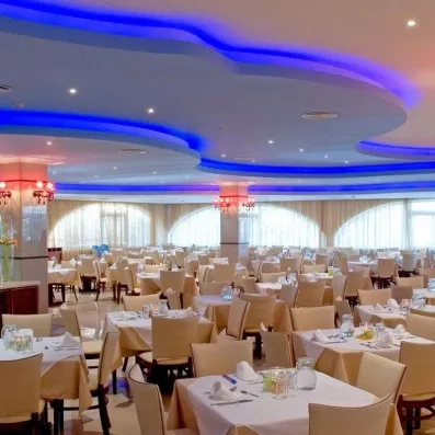 restaurant avec tables et chaises blanc beiges, plafond bleu violet, grands rideaux blancs