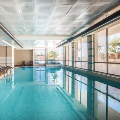 Une vue en longueur de la piscine intérieure, reflétant la lumière du jour.