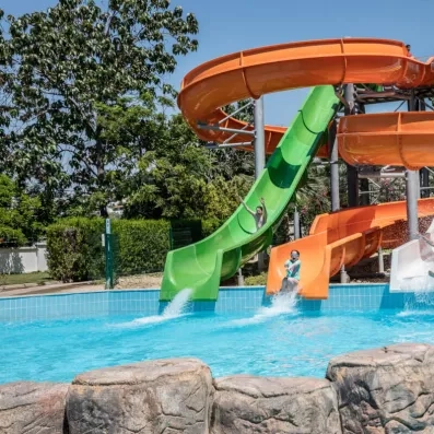 Des enfants s'amusant à glisser sur des toboggans aquatiques, sous un ciel bleu.