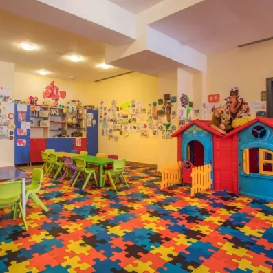 Une salle de jeux pour enfants avec des tables d'activités et une petite cabane.