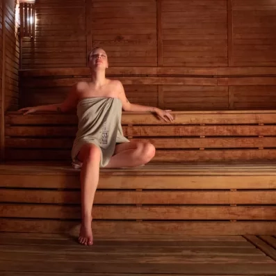Une femme se relaxant sereinement sur les bancs en bois d'un sauna chaleureux.