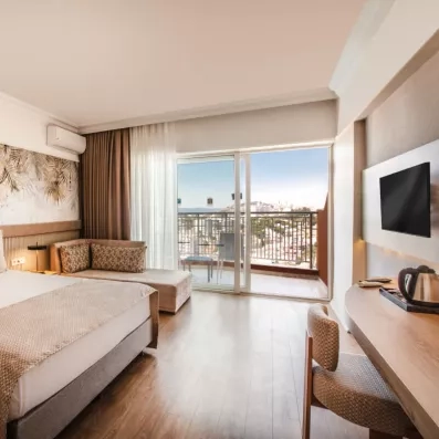 Une chambre spacieuse avec un coin bureau, une télévision et une grande baie vitrée.