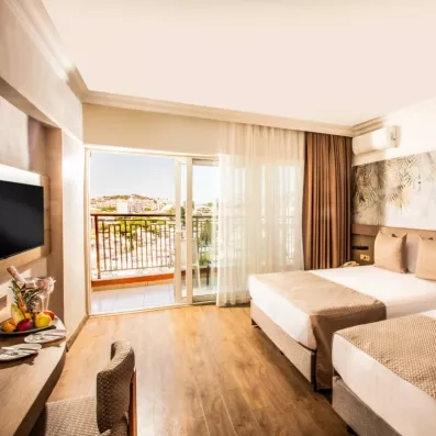 Une chambre avec deux lits simples, ouvrant sur un balcon ensoleillé.