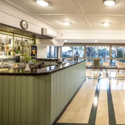 Un bar intérieur élégant, offrant une vue dégagée sur l'extérieur à travers de grandes baies vitrées.