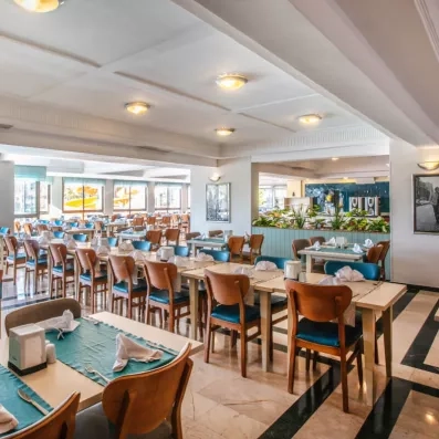 Une vaste salle de restaurant lumineuse, avec des tables bien alignées.