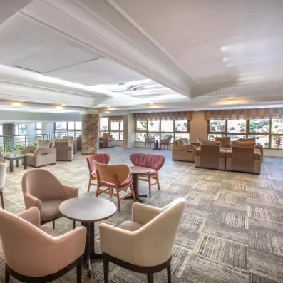 Un salon d'accueil spacieux, doté de nombreux fauteuils et de grandes baies vitrées.