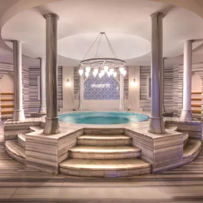Un somptueux bain turc circulaire, orné de colonnes en marbre et de mosaïques bleues.