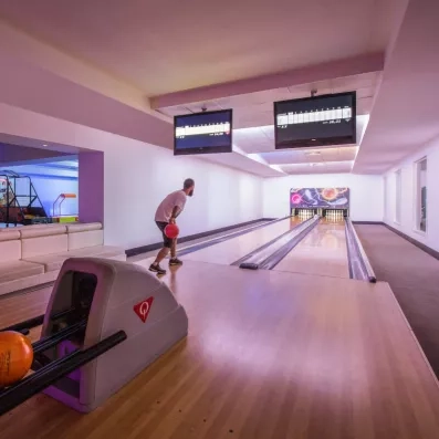 Une salle de divertissement comprenant des pistes de bowling et des écrans de score.