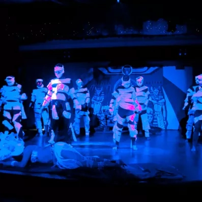 Une troupe de danseurs sur scène réalisant un spectacle sous des lumières bleues.