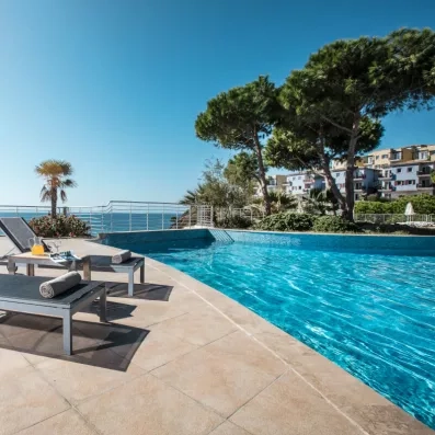 Une piscine à débordement offrant une vue imprenable sur la mer et les jardins.