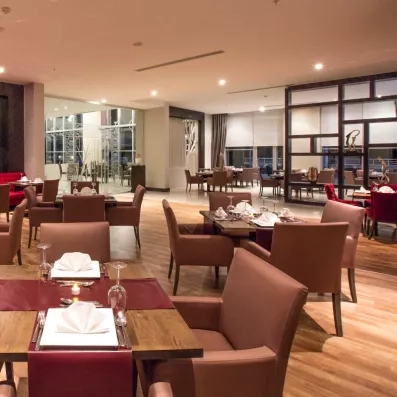 Une salle de restaurant spacieuse, équipé d'un mobilier boisé et de fauteuils.