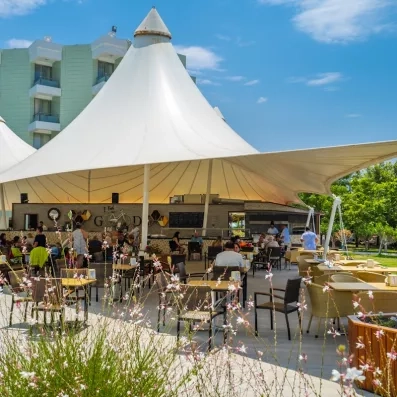 Une terrasse ombragée par de grandes tentes blanches offre un espace en plein air près du jardin.