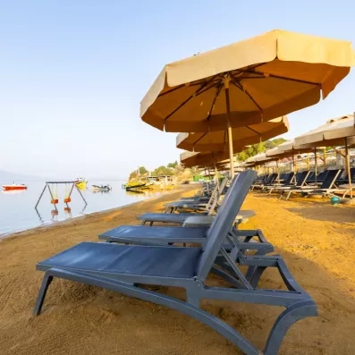 Une plage de sable paisible bordée de rangées de transats et de parasols.