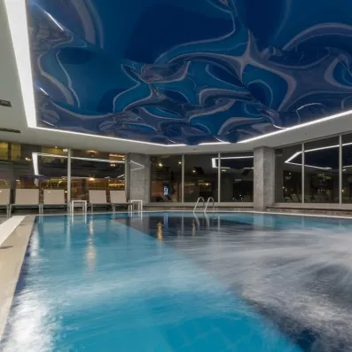 Une piscine intérieure élégante sous un plafond bleu design ondulé.