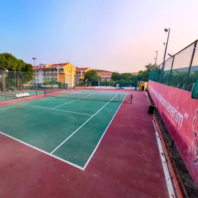 Des terrains de tennis extérieurs professionnels, sous un ciel de fin de journée.