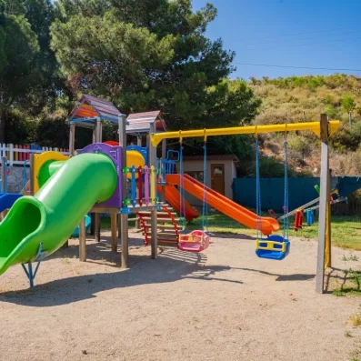 Une aire de jeux extérieure, comprenant des toboggans et des balançoires.