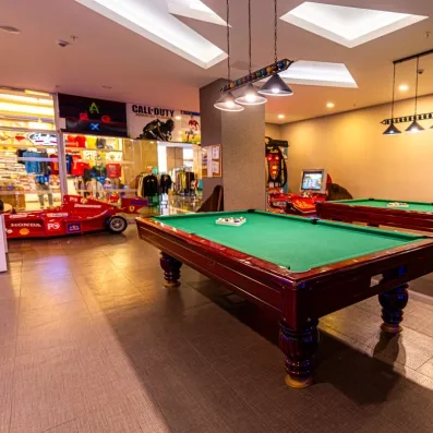 Une salle de jeux disposant de plusieurs tables de billard et de bornes d'arcade.