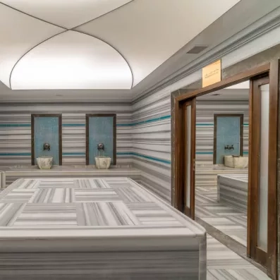Un hammam traditionnel spacieux, entièrement revêtu de marbre gris et blanc.