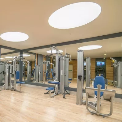 Une salle de fitness lumineuse équipée de machines de musculations et de miroirs.