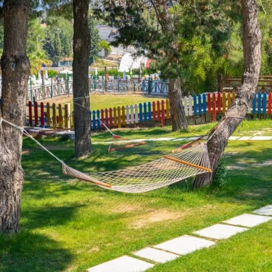 Des hamacs en filet suspendus entre les arbres dans un jardin verdoyant.