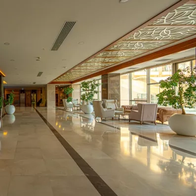 Un long passage lumineux, agrémenté de fauteuils confortables et de grandes plantes vertes.