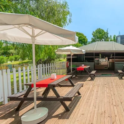 Une aire de restauration en plein air avec des tables de pique-nique se trouve sous des parasols.