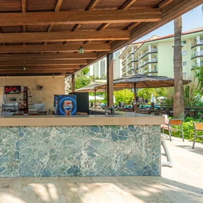 Un bar de piscine décontracté avec un comptoir en marbre offre une vue sur un complexe hôtelier.