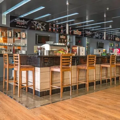 Un café d'hôtel contemporain dispose d'un comptoir en bois et en marbre avec des tabourets.