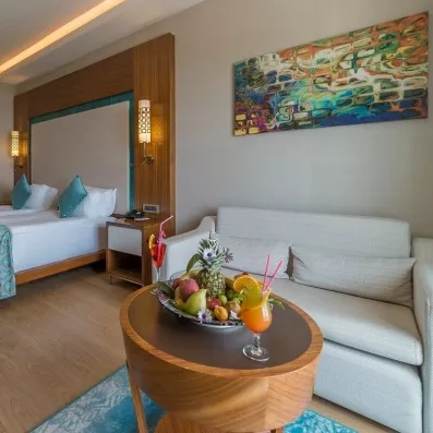 Une chambre avec un canapé et une table basse garnie de fruits et de cocktails.