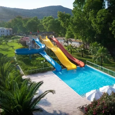 Un parc aquatique extérieur avec trois grands toboggans, plongeant dans une piscine.