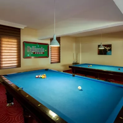 Une salle de jeux intérieure comprenant deux tables de billard sous un éclairage tamisé.