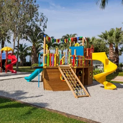 Une aire de jeux extérieure pour enfants, située sur un sol en gravier blanc.