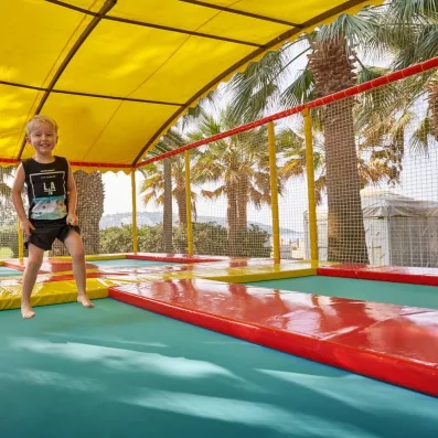 Un enfant s'amusant sur un trampoline protégés par une bâche pour l'ombrage.