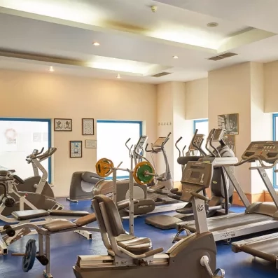 Une salle de sport équipée de nombreux appareils de cardio-training et des tapis de course.