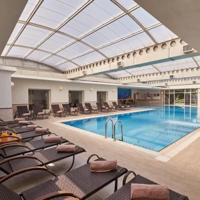 Une piscine couverte, bordée de transats confortables sous une grande verrière.