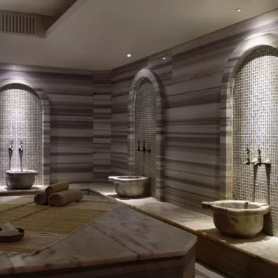 Un somptueux hammam traditionnel en marbre doté de vasques à eau.