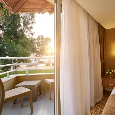 Un balcon ensoleillé avec deux fauteuils offrant une vue apaisante sur la végétation.