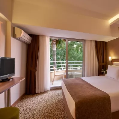 Une chambre avec un lit double et un balcon privé donnant sur des jardins.