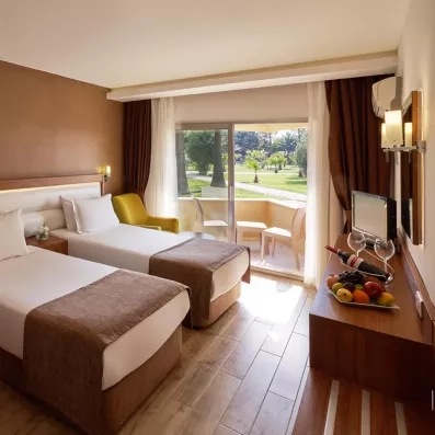 Une chambre lumineuse avec deux lits simples, un fauteuil et d'un plateau de bienvenue.